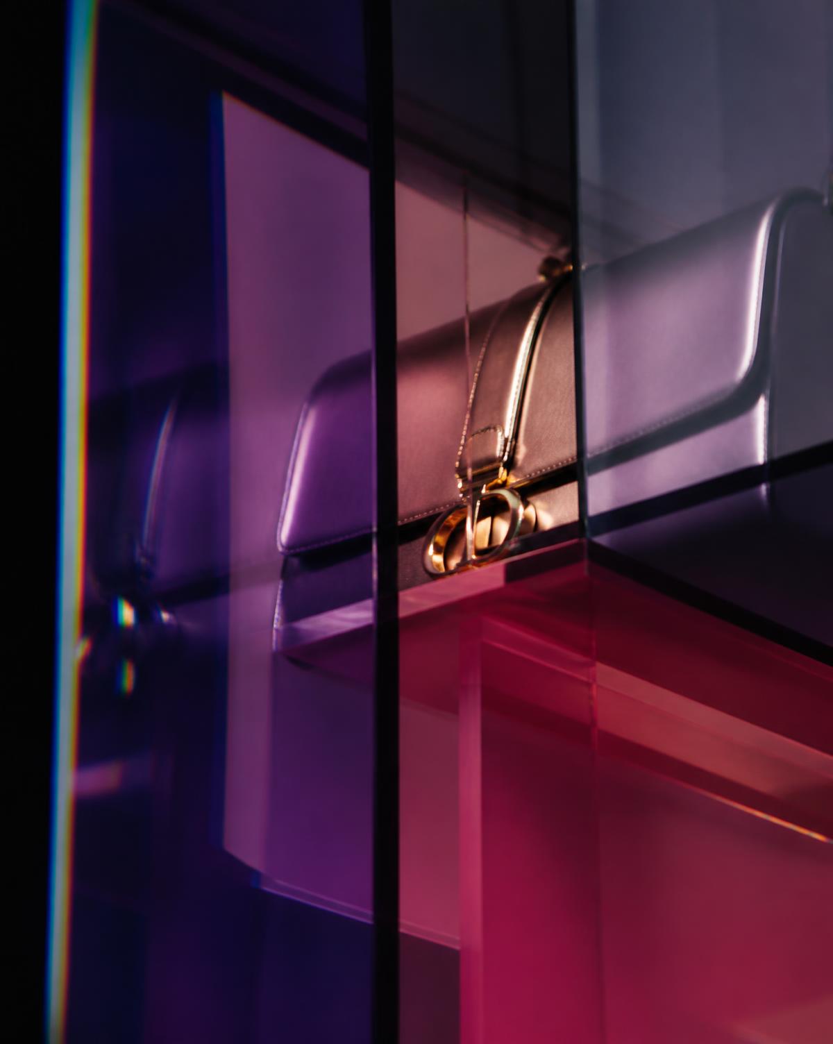 Close crop of a luxury handbag seen through overlapping violet and magenta glass panes